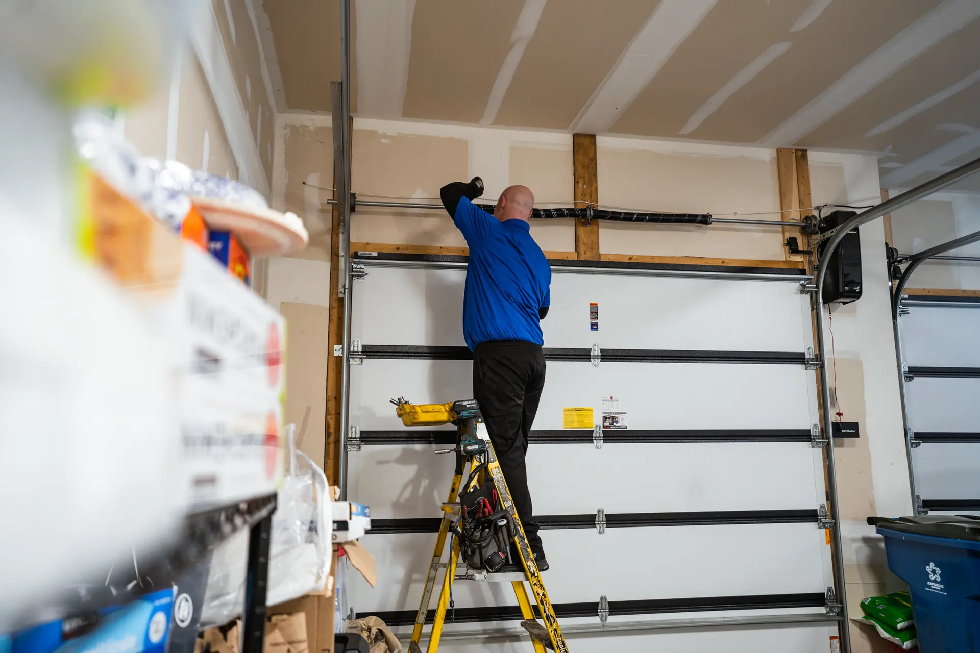 A man dong repairs or tuning up a garage door.
